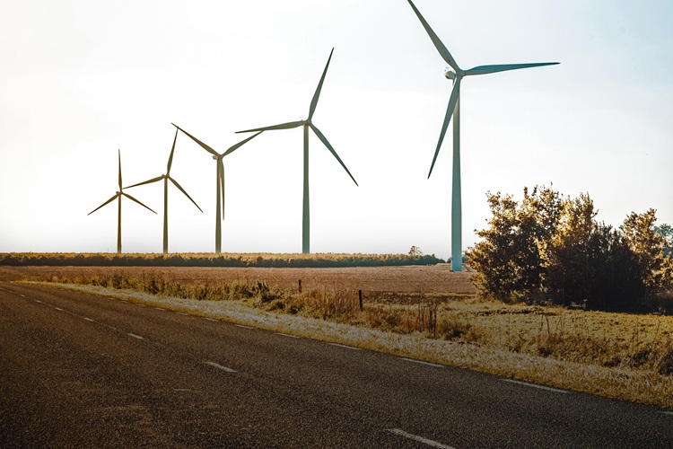 Wind turbines on land by road against Sky