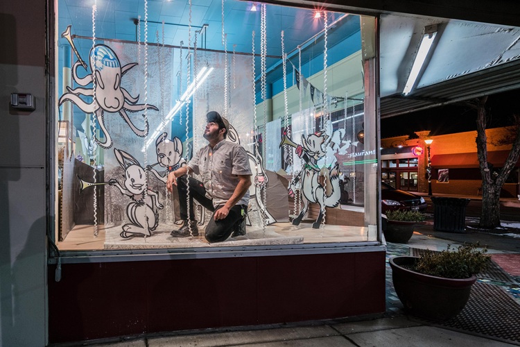 man decorating display window in music store
